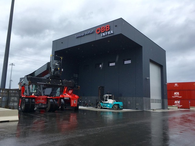 A large EFAFLEX high speed door in the loading bay of a rail freight terminal, with reach stackers and container handlers parked outside