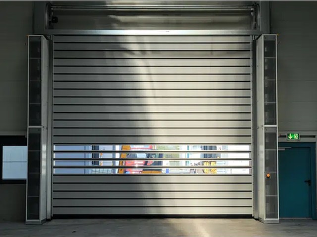 A large EFAFLEX high speed door installed in an industrial hall, with a full width vision panel across the door leaf