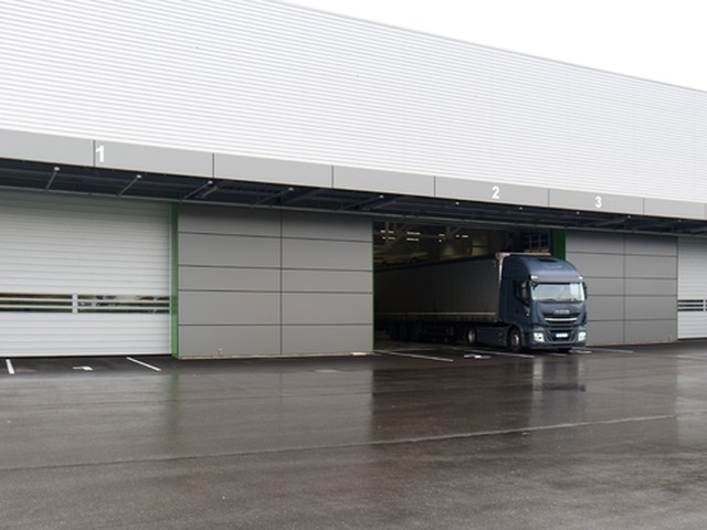 An articulated lorry emerges from an open loading bay in a row of numbered bays, with white EFAFLEX high speed doors closed either side